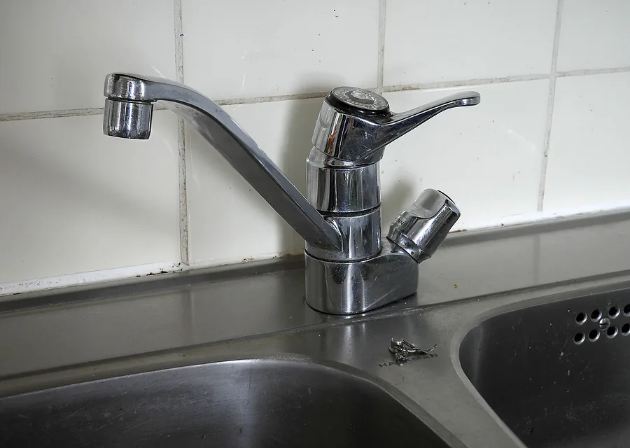 A chrome single lever mixer tap on a stainless steel kitchen sink.
