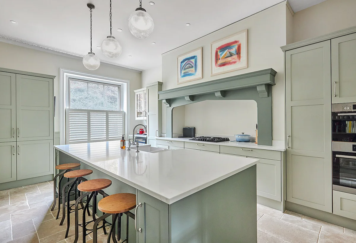 A kitchen with glass pendant lights over the island and downlights across the ceiling.
